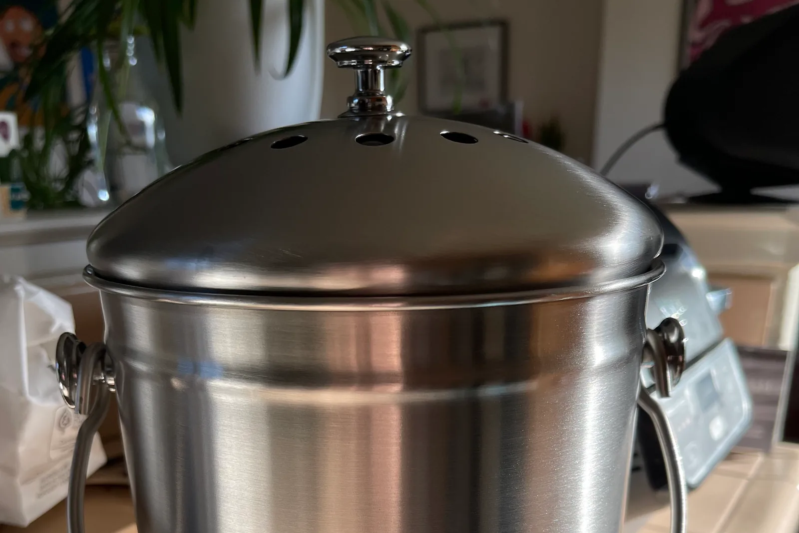 A compact stainless steel food-scrap pail on a kitchen counter.