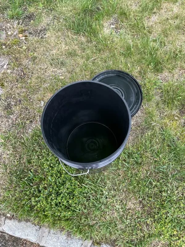 Top-down view of a clean, sealed Torus bucket at a door, showing composting is tidy and odor-free.