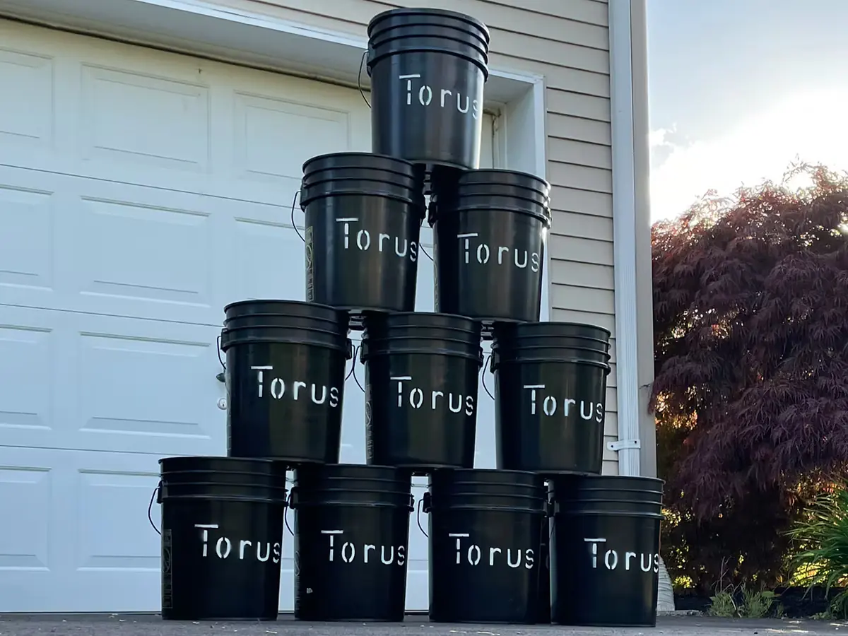 Pyramid of stacked Torus compost buckets in front of a garage door