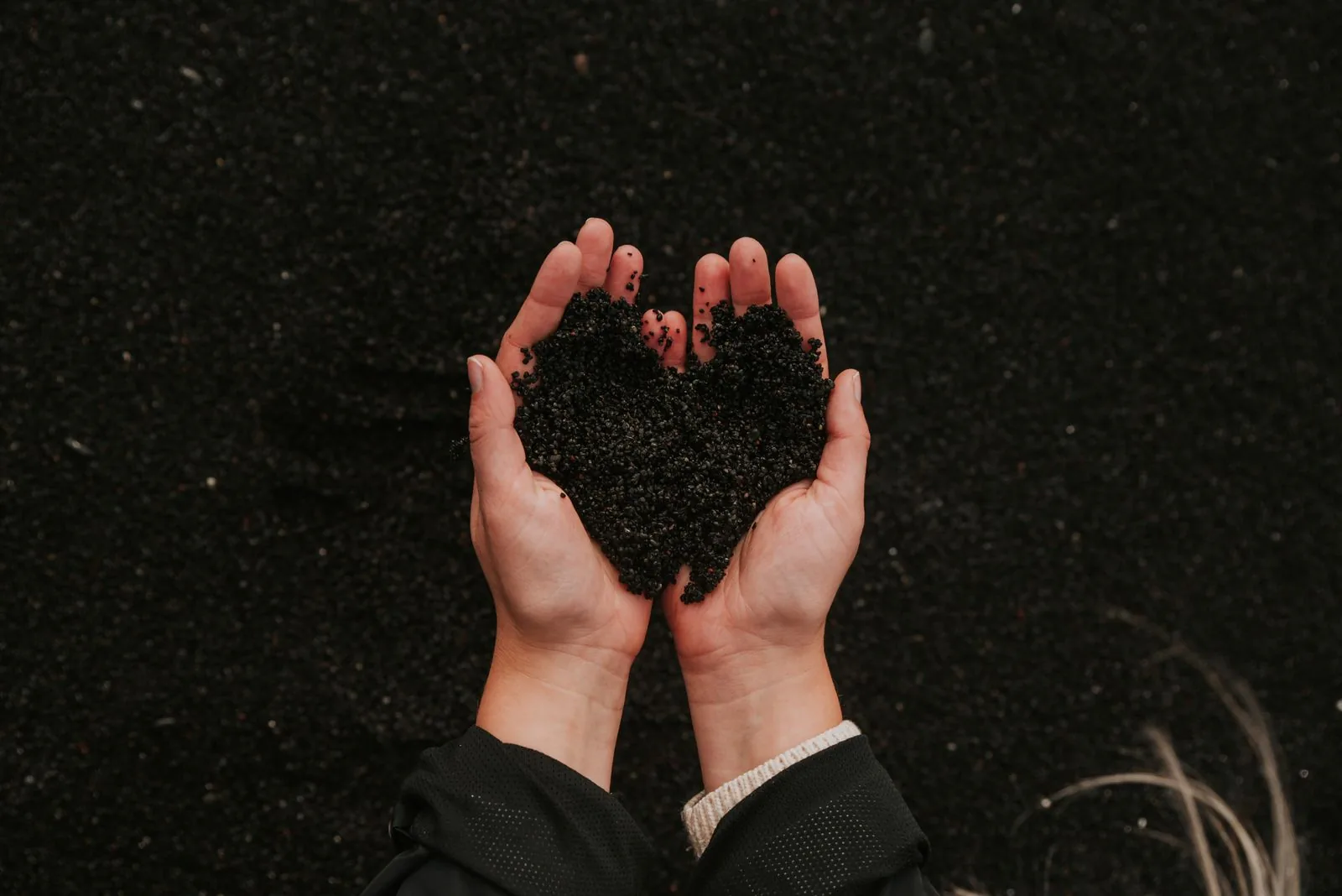 Hands cradling dark, finished compost soil shaped like a heart, representing the environmental impact of diverting food waste