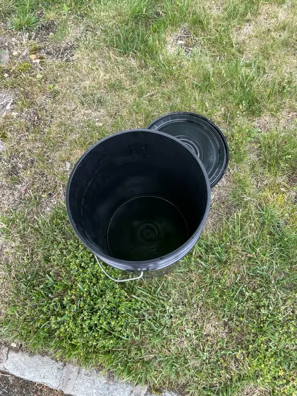 Top-down view of a clean, sealed Torus bucket at a door, showing composting is tidy and odor-free.