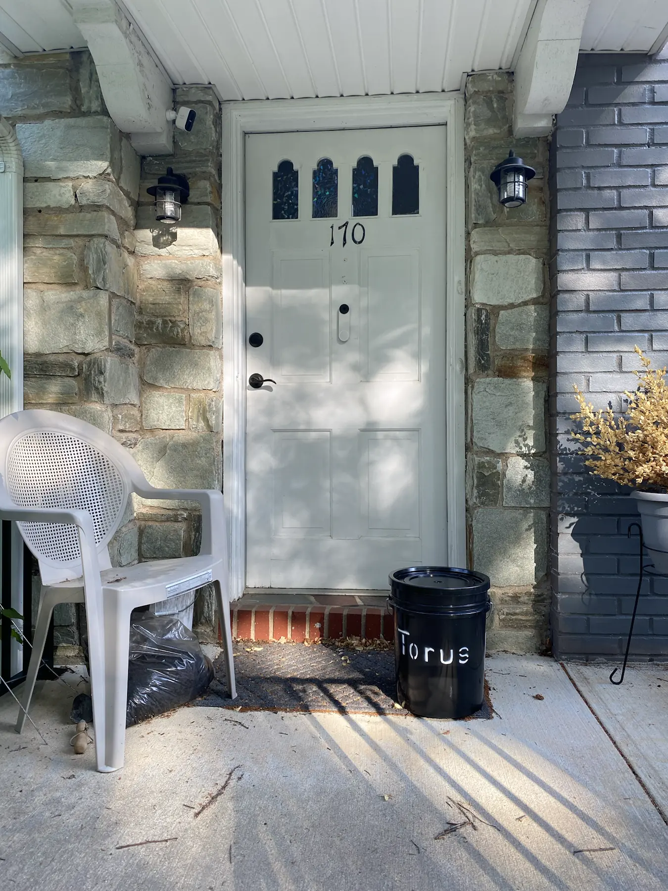 A Torus compost bucket sitting on a residential front doorstep, ready for pickup.