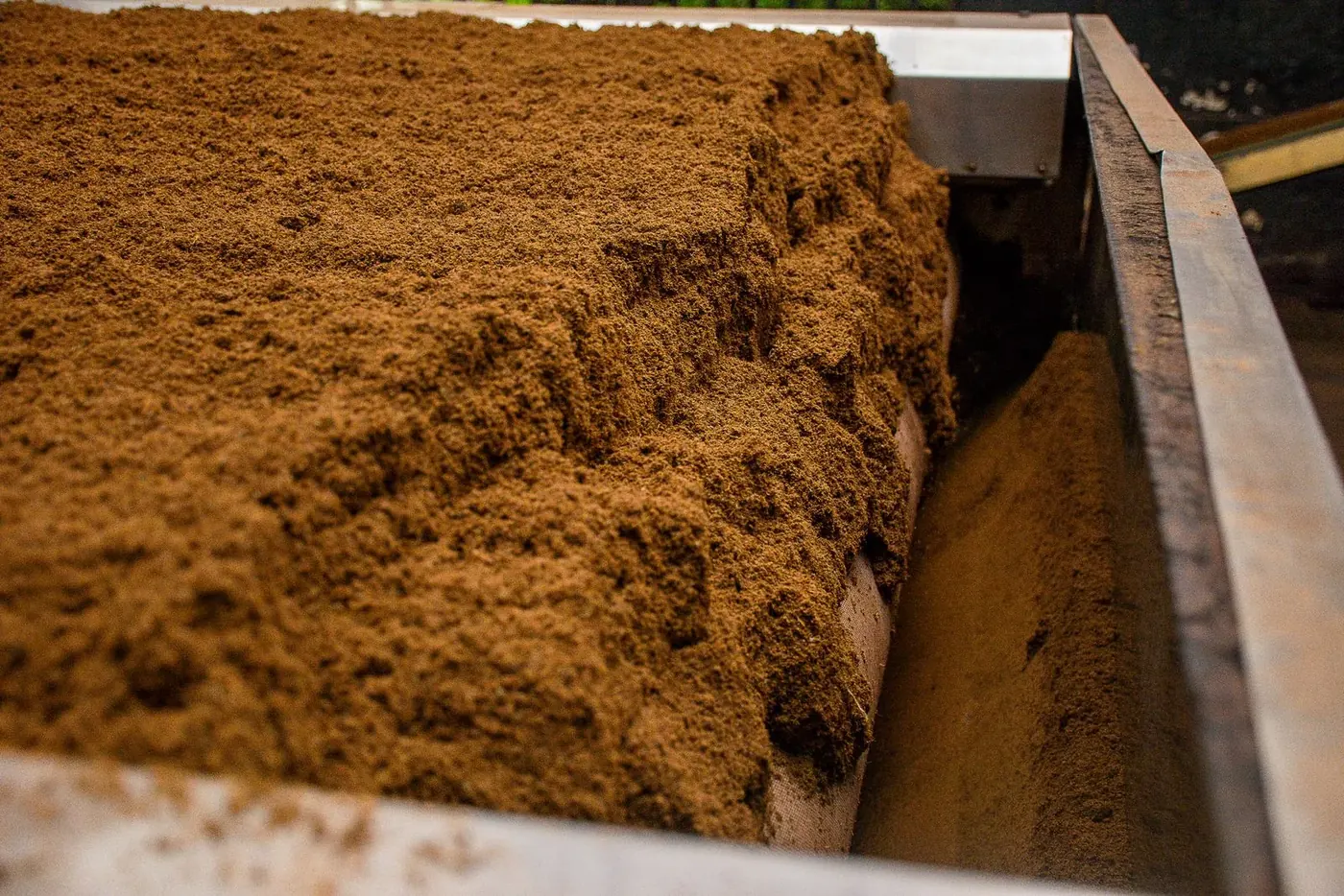 Processed organic material moving through an enclosed industrial composting vessel.