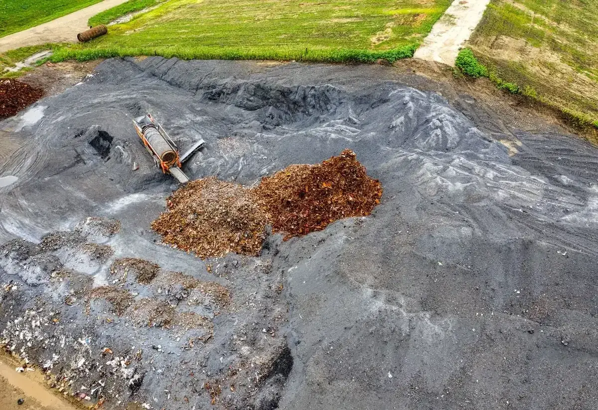 Large compost piles and processing equipment at an aerated static pile facility.