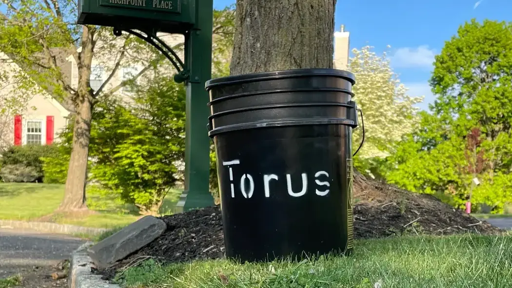 A Torus food-scrap bucket beside a residential mailbox, ready for curbside pickup.