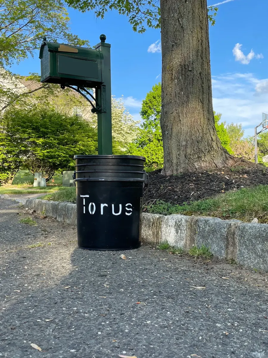 Torus compost bucket placed beside a residential mailbox for curbside pickup signup